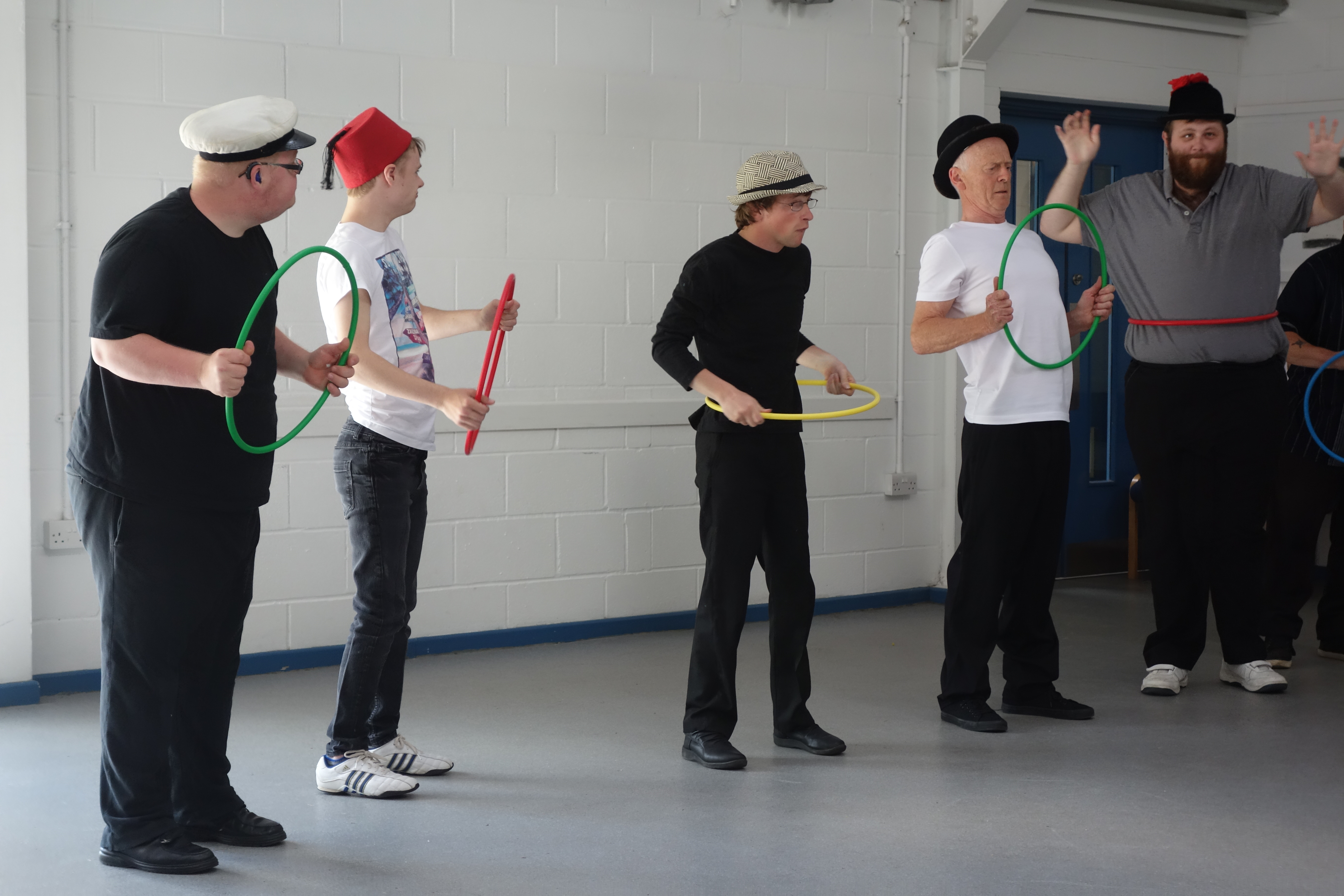 five people dancing in a room with coloured hoops in their hands