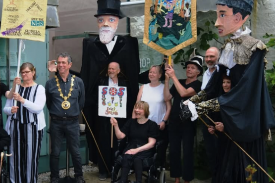 giant puppets of Mr and Mrs Passmore with banners outside Newlyn Art Gallery
