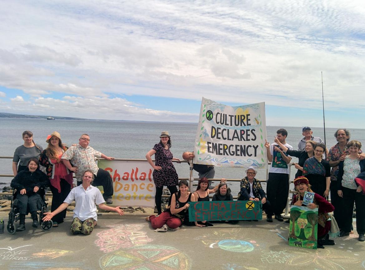 People gather on Penzance promenade with a banner saying culture declares emergency