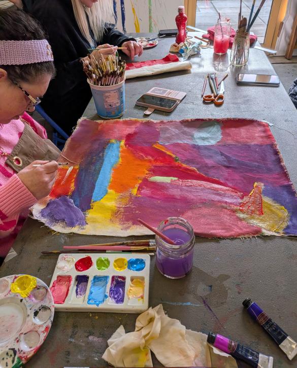 bright multi coloured painting with womans head and her hand on the left