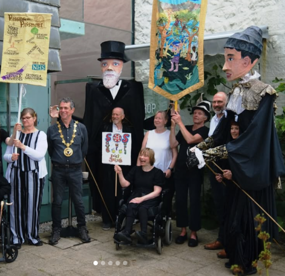giant puppets of Mr and Mrs Passmore with banners outside Newlyn Art Gallery