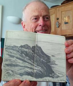 person holding sketchbooks with sketch of cliffs