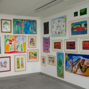 Paintings and drawings in frames hanging on a wall in an art gallery