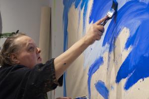 person painting a blue abstract painting