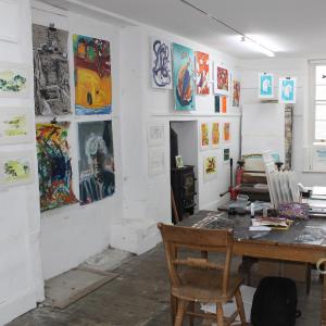 An art studio with artwork on the walls and a table in the middle displaying smaller artwork