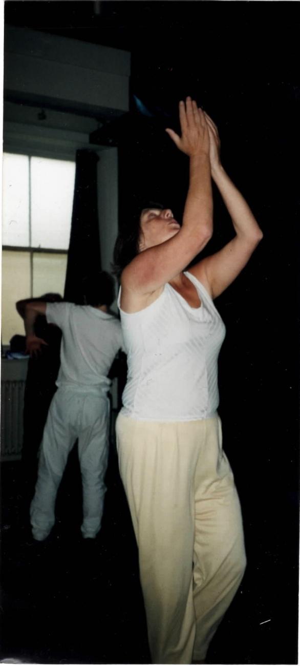 a person dancing in all white with their arms raised above their head